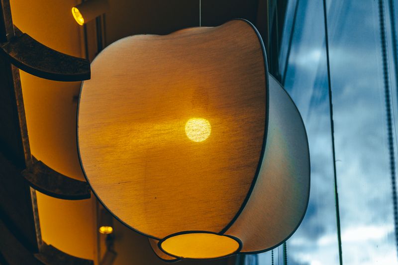 Lámpara colgante de luz cálida recortada contra una ventana de luz fría